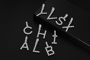 Close-up of iced out silver letter pendants with pave set cubic zirconia stones