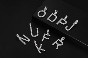 Close-up of iced out silver letter pendants with micro-paved 4mm cubic zirconia stones