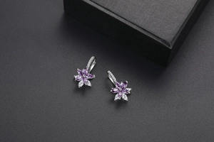 Détail macro de boucles d'oreilles fleurs en argent avec pierres marquises violettes