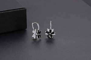 Détail macro de boucles d'oreilles fleurs à deux couches avec zircons noirs et base argent