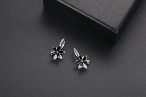 Détail de boucles d'oreilles fleurs double couche serties de zircons noirs et blancs