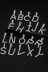 Macro view of iced out silver letter pendants with pave set cubic zirconia stones