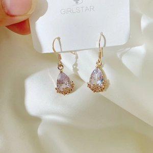 Detailed close-up of teardrop purple zirconia earrings with golden hollow filigree pattern