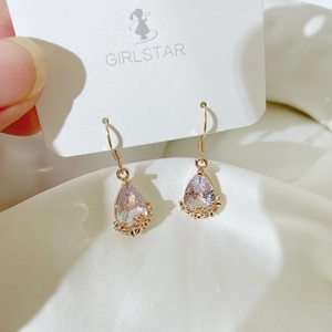 Close-up of elegant gold plated pear-cut purple zircon earrings on white satin