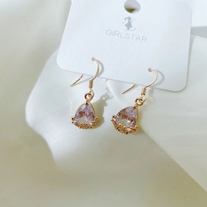 Macro detail of teardrop purple zircon earrings with golden floral hollow design