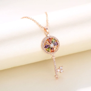 Macro detail of rose gold key pendant featuring colorful pear-cut gemstones and tiny zircons
