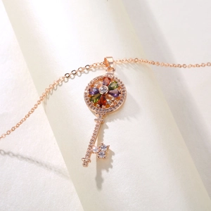 Close-up of rose gold key pendant with colorful pear-shaped gemstones and sparkling crystals