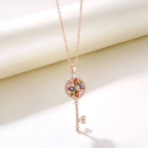 Macro view of rose gold key pendant with colorful floral gemstones and pave crystals
