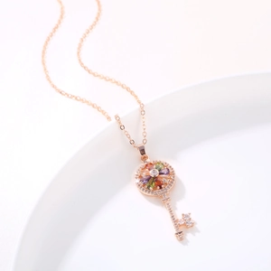 Rose gold key pendant necklace with colorful birthstones on a white ceramic plate