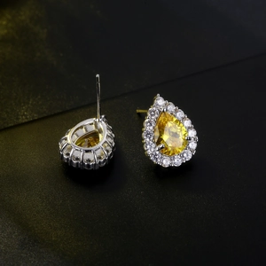 Macro detail of pear-cut yellow zircon earrings with halo micro-pave setting on silver