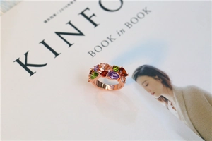 Bague en or rose avec cristaux colorés taille poire sur un magazine minimaliste