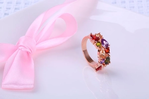 Détail de la bague en or rose avec cristaux colorés sur un ruban de soie rose