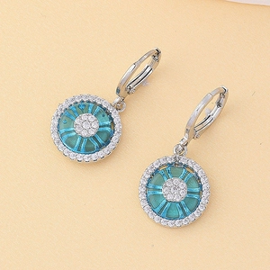 Détail des boucles d'oreilles créoles argentées avec centre bleu et halo de cristaux