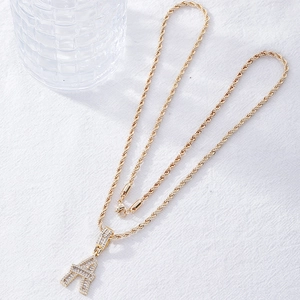 Gold twist chain necklace featuring a zircon encrusted Eiffel Tower pendant on fabric