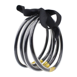 Vista detallada de pulseras de silicona con purpurina multicapa, lazo negro y cierre metálico