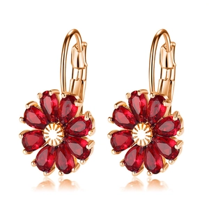 Close-up of rose gold floral earrings featuring pear-cut dark red zircon petals