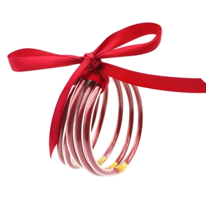 Detalle de pulseras de silicona roja con purpurina y un lazo de cinta de satén