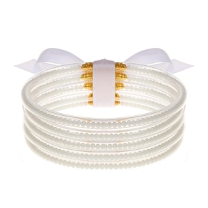 Detalle de brazaletes de silicona blanca rellenos de cuentas y un lazo decorativo