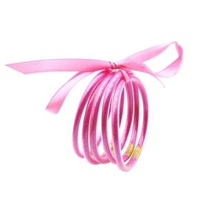 Vista macro de pulseras de silicona con purpurina rosa atadas con un lazo de satén fino