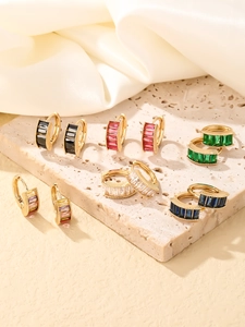 Macro shot of six pairs of gold alloy hoop earrings with colorful rectangular zircon