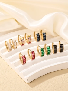 Set of gold hoop earrings with colorful rectangular zircon stones on silk fabric