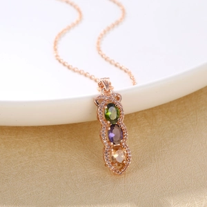 Detalle de collar de oro rosa con un colgante con tres piedras preciosas ovaladas