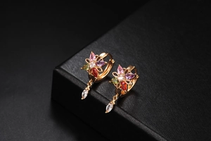 Close-up of gold floral earrings with colorful zirconia petals and drop pendant