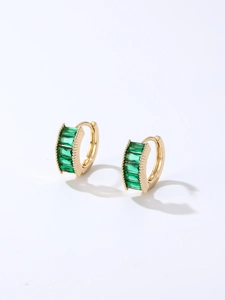 Detail of gold hoop earrings featuring channel-set rectangular green cubic zirconia
