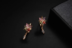 Macro view of colorful floral zircon drop earrings featuring a gold teardrop pendant detail