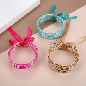Set de tres pulseras de silicona multicapa con cuentas internas y lazos de seda en oro