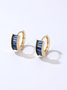 Macro detail of gold hoop earrings with vertical set dark blue baguette-cut zircons