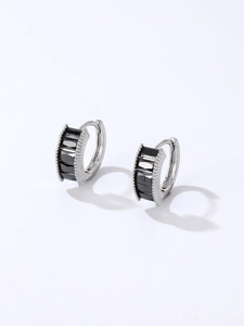 Macro shot of silver earrings with baguette-cut black zircons and striped engraving