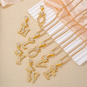 Collana con lettera a corona dorata con pavé di zirconi su elegante sfondo di seta
