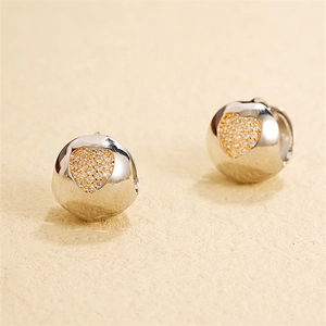Dettaglio di orecchini a sfera in argento con cuore dorato e zirconi cubici scintillanti