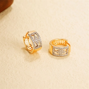 Detail of 18k gold earrings with geometric hollow design and pavé zircon stones
