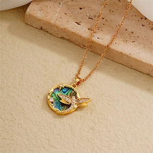 Macro view of 18K gold plated necklace with abalone shell heart and zircon dragonfly