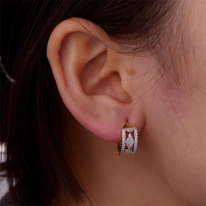 Macro view of 18k gold hoop earring featuring geometric zircon inlay on a model