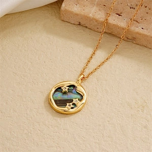 Macro detail of 18K gold plated necklace with iridescent abalone shell and zircon stars