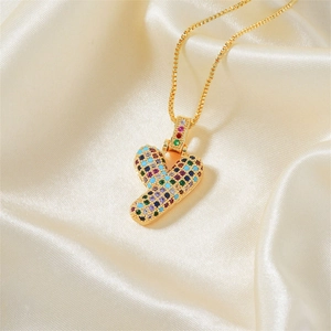 Dettaglio di una collana con ciondolo a cuore dorato e zirconi colorati su raso di lusso
