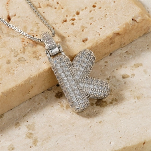 Close-up of iced out letter K pendant with cubic zirconia inlay and box chain