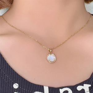 Dettaglio della collana dorata con ciondolo smile in madreperla bianca da donna