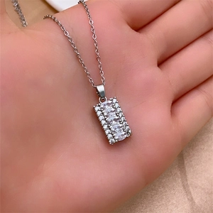 Dettaglio di un ciondolo rettangolare d'argento con pietre marquise tenuto in mano