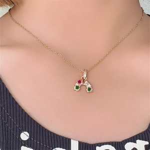 Dettaglio di una collana a cuore in oro con pietre preziose colorate su una modella