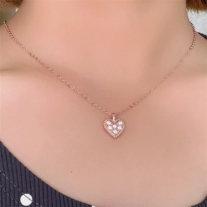 Primo piano della collana a cuore in oro rosa con zirconi bianchi sul collo