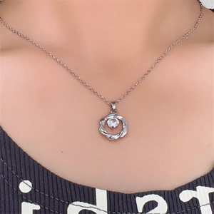 Dettaglio di una collana in argento con anello intrecciato e ciondolo in zircone su modella