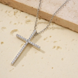 Collar de cruz de plata con circonitas blancas brillantes sobre superficie de piedra