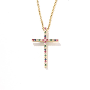 Collar con colgante de cruz dorada con piedras preciosas de colores sobre fondo blanco