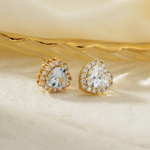 Macro detail of heart-shaped zircon earrings with gold plating and sparkling halo stones
