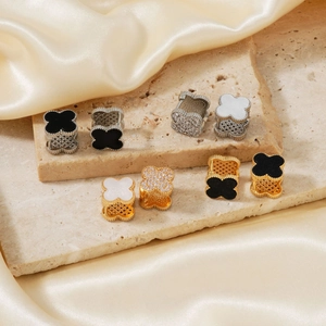 Boucles d'oreilles trèfle avec onyx noir, nacre et zircon sur fond de soie luxueux
