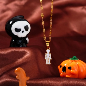 Halloween skeletal doll pendant on gold necklace over dark brown silk satin backdrop